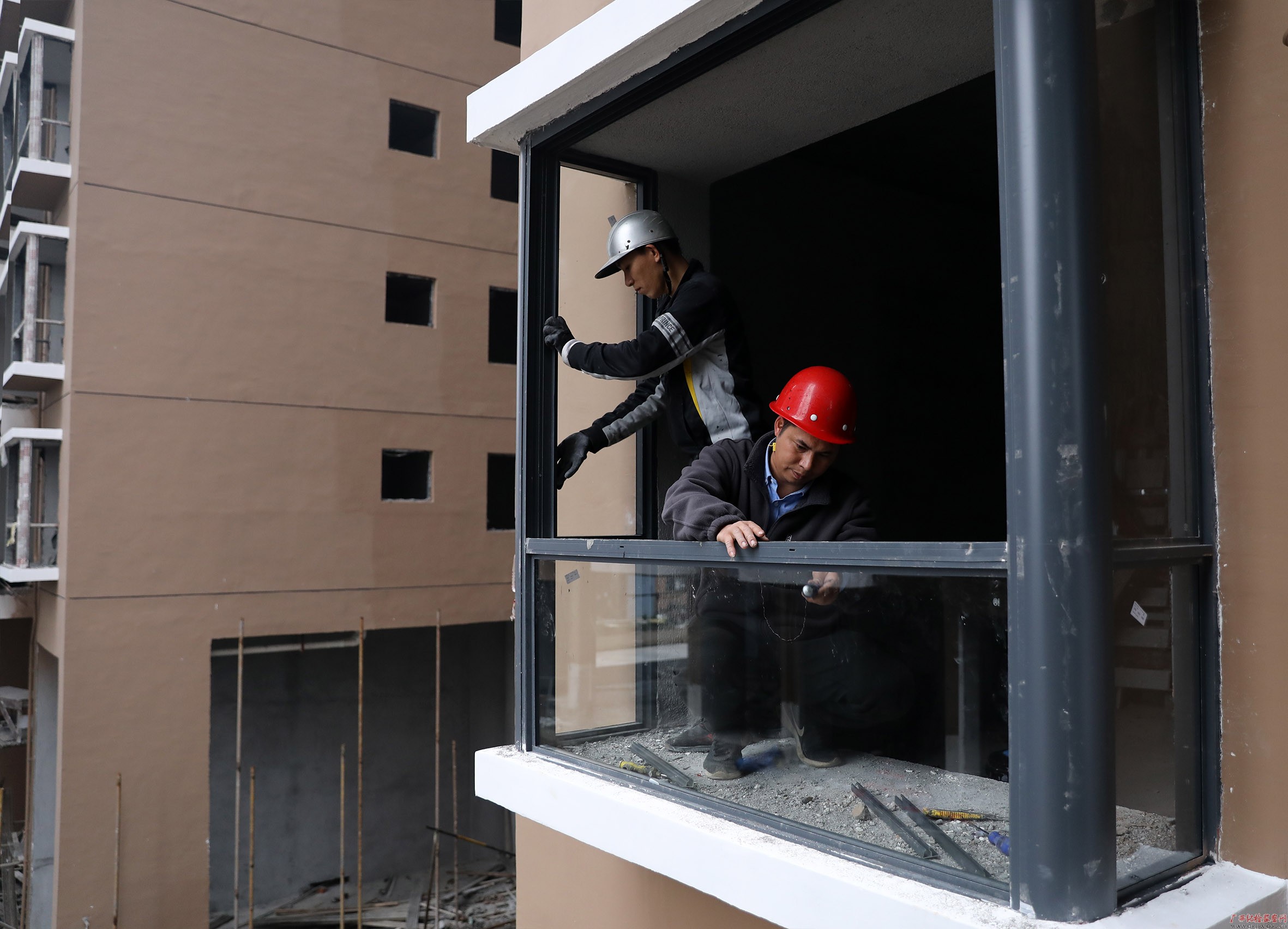贲仕群(前)和工友在阳光丽苑小区安装窗户