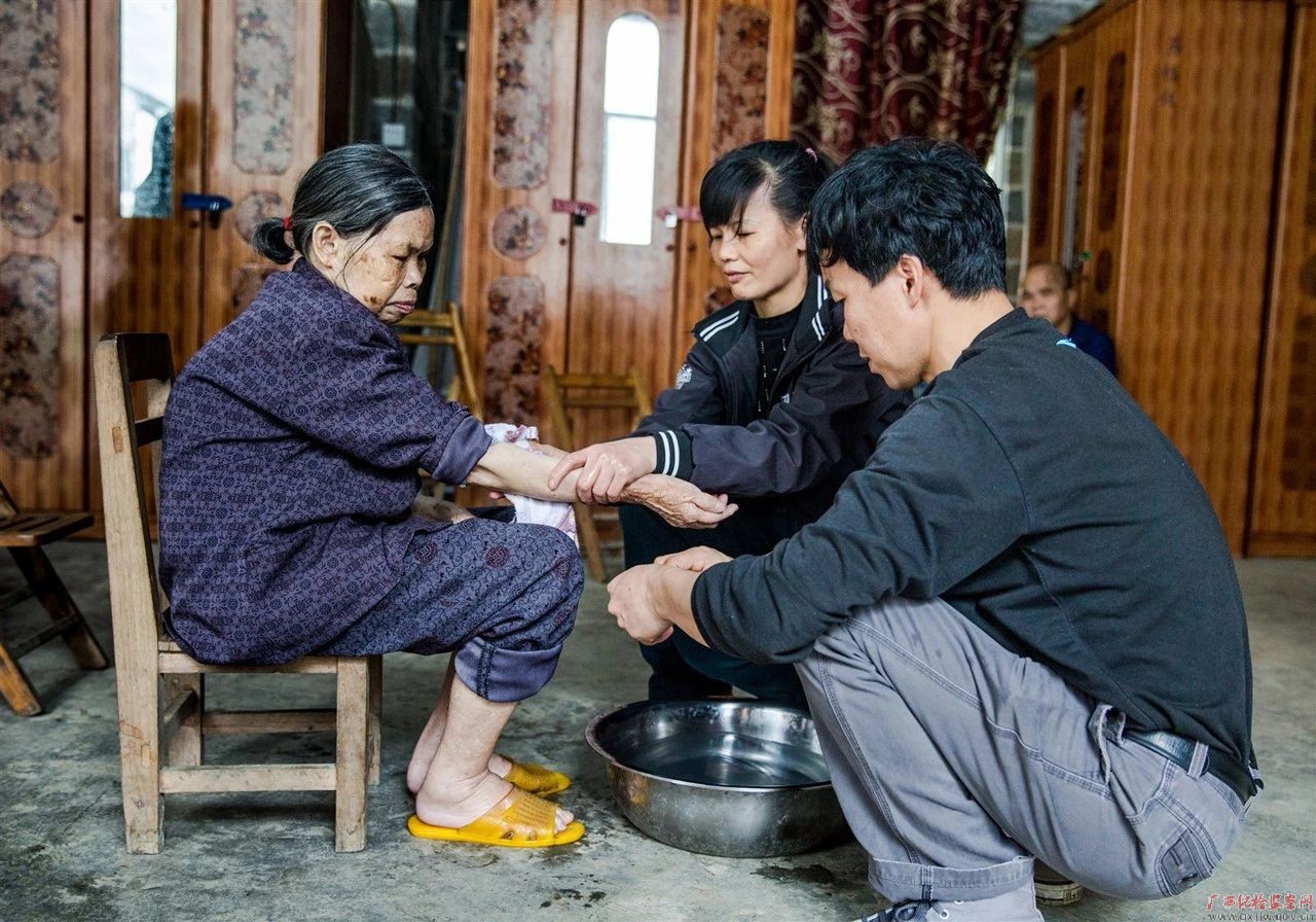 图为唐翠玉和爱人给老人洗脚抹身(覃柳腾摄)